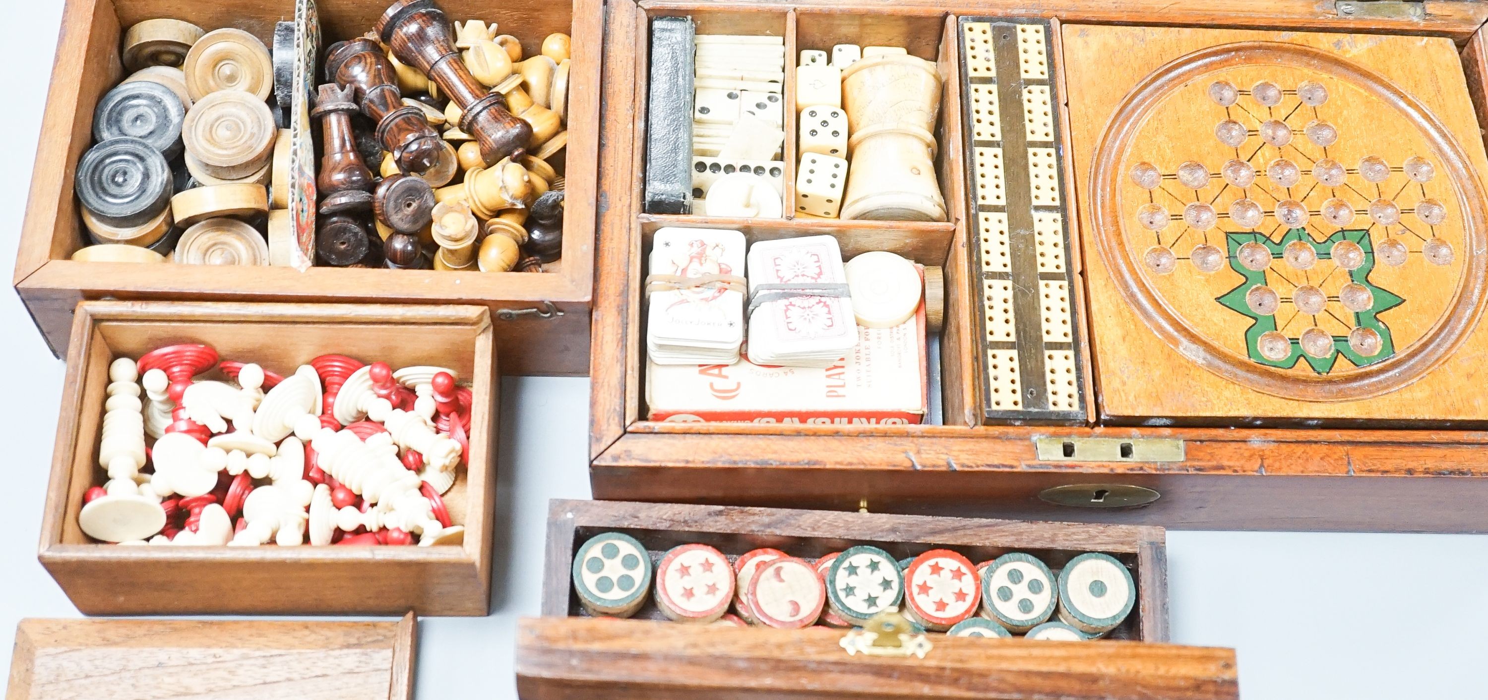 A Victorian brass inset mahogany games box, fitted with solitaire, cribbage, chessmen, draughts etc., 33cm, a turned and stained bone chess set, another games box containing chessmen and draughts
